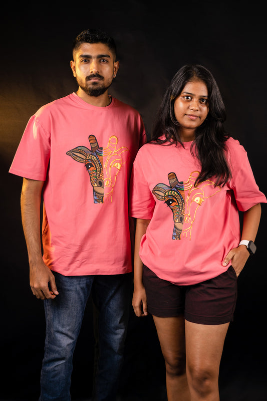 A man and a woman standing next to each other, wearing pink crew neck Trives T-shirts with a gold and multi colored puff printed giraffe tshirt .
