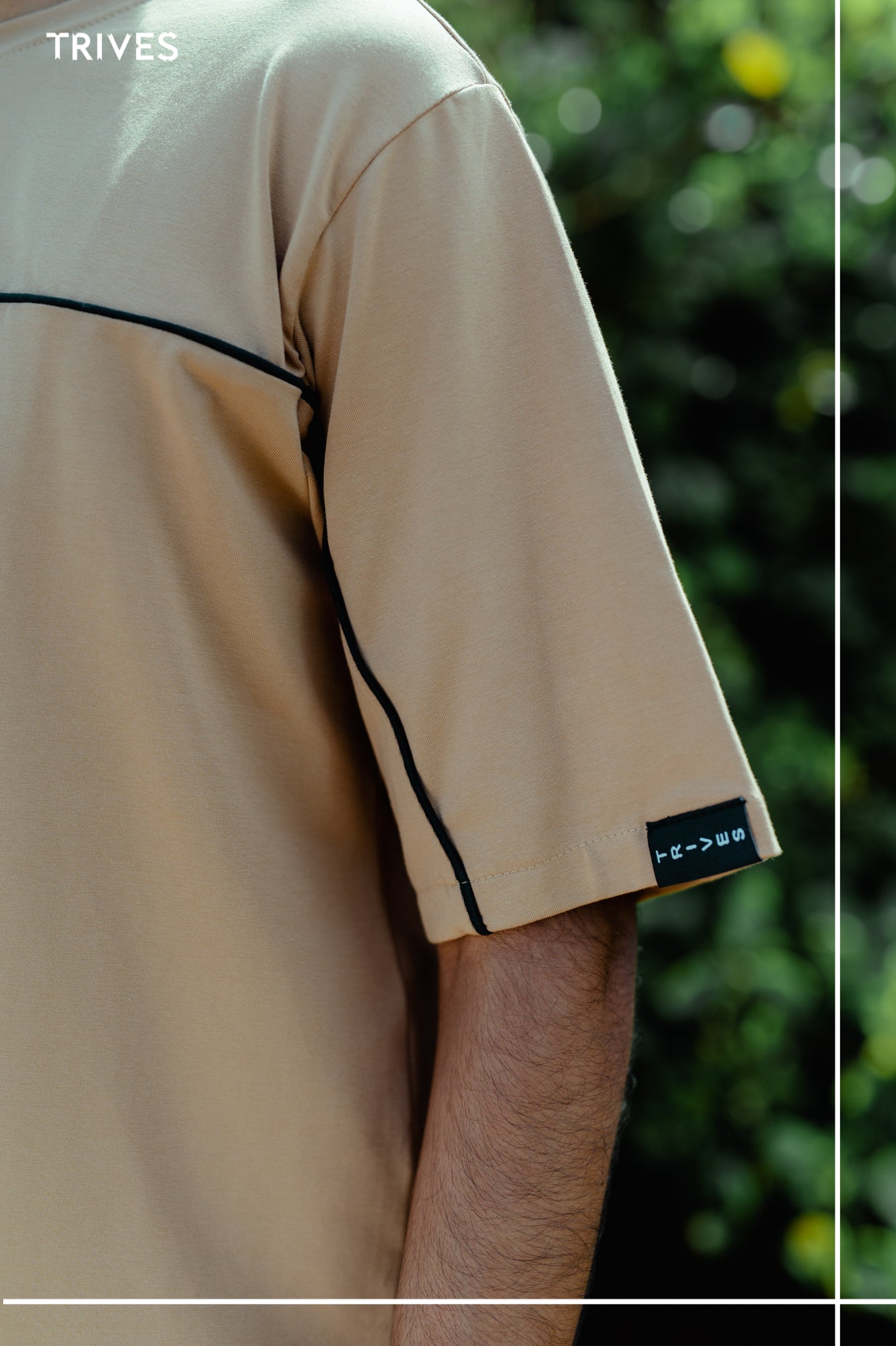TRIVES Horizon Beige shirt with black trim worn by a person, blurred green background