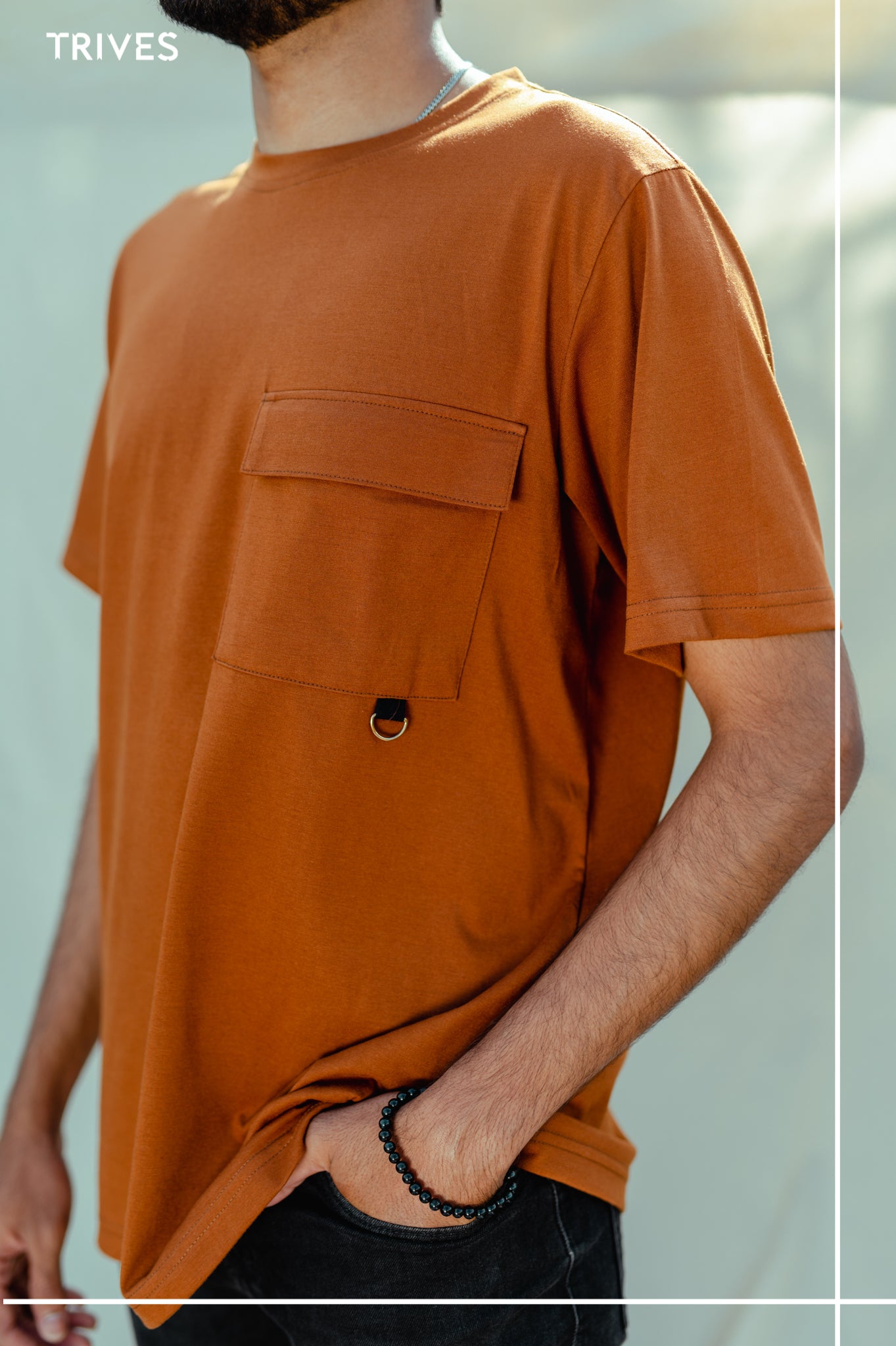 Person wearing a brown cocoa stash tee/t-shirt with a pocket against a blurred background