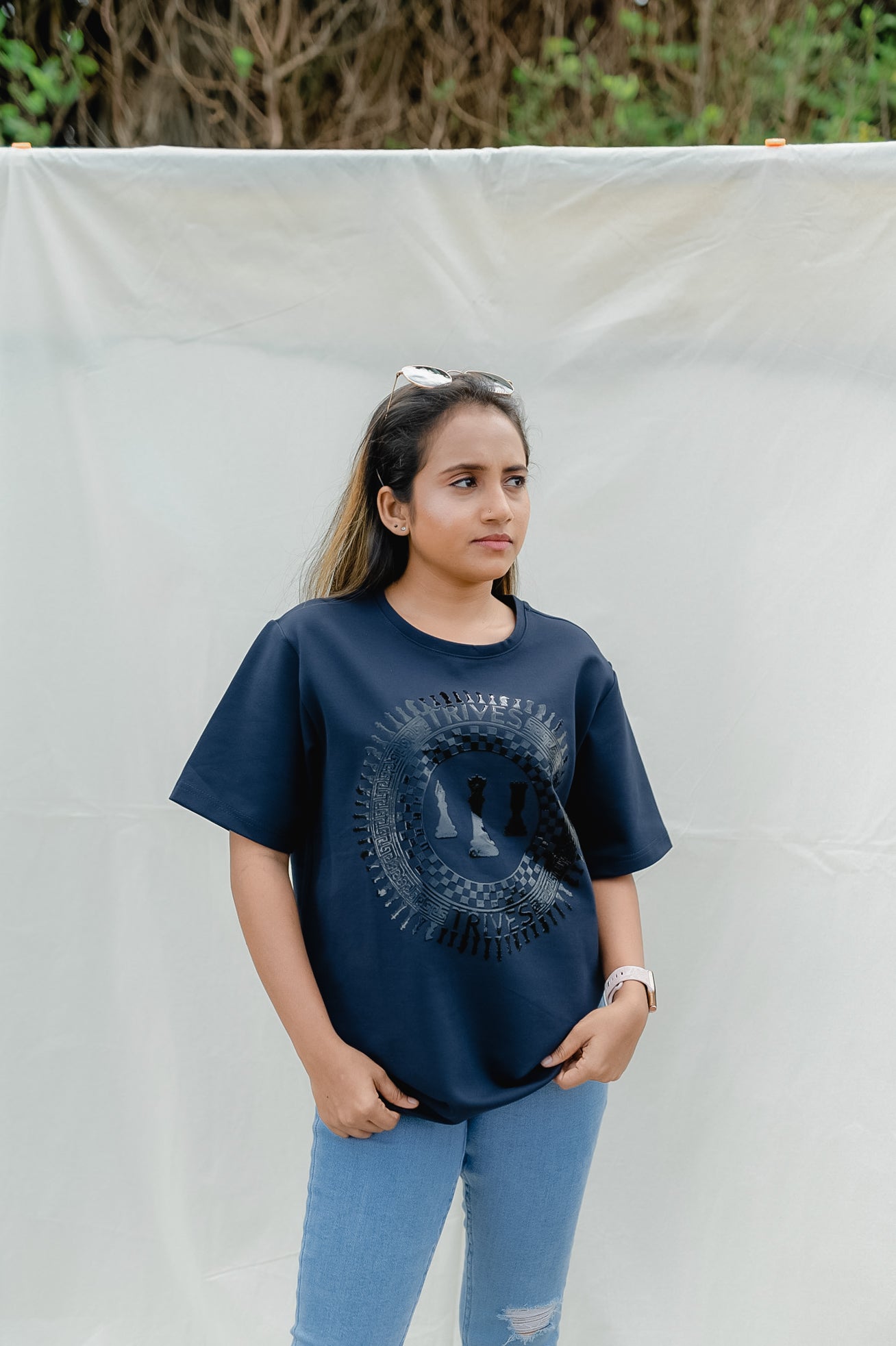 Woman wearing a navy blue t-shirt with a graphic design, standing against a plain background.